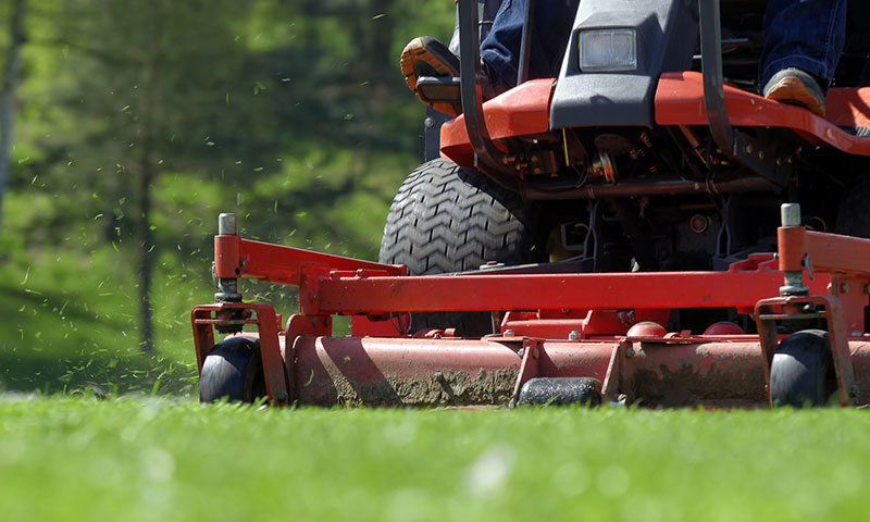 Landscaper mowing commercial lawn.