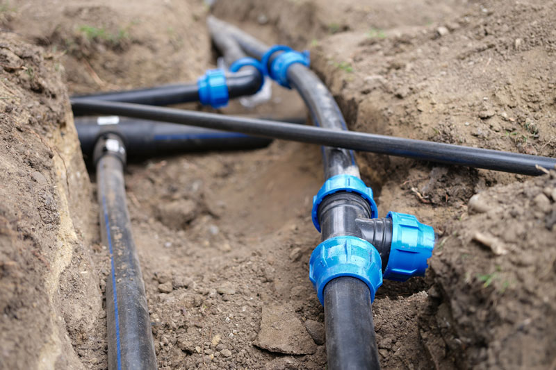 Landscape irrigation tubes and connectors exposed in trenches.