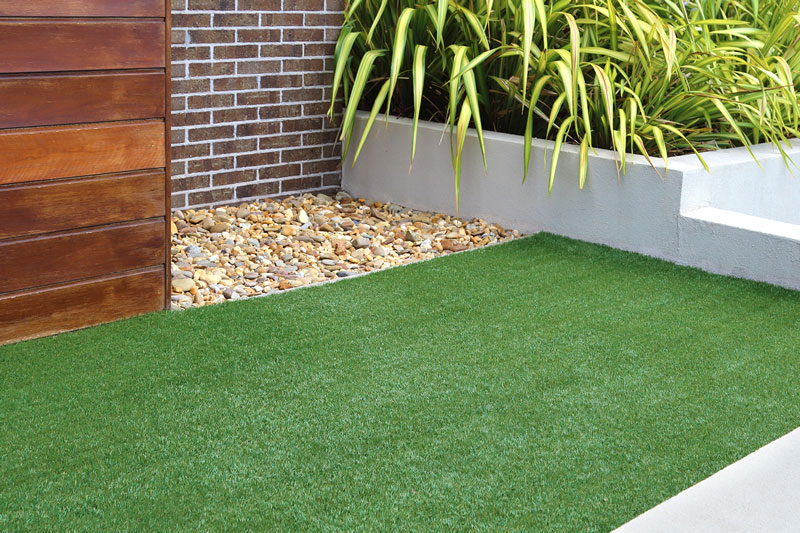 Artificial turf grass in place with rock ground cover