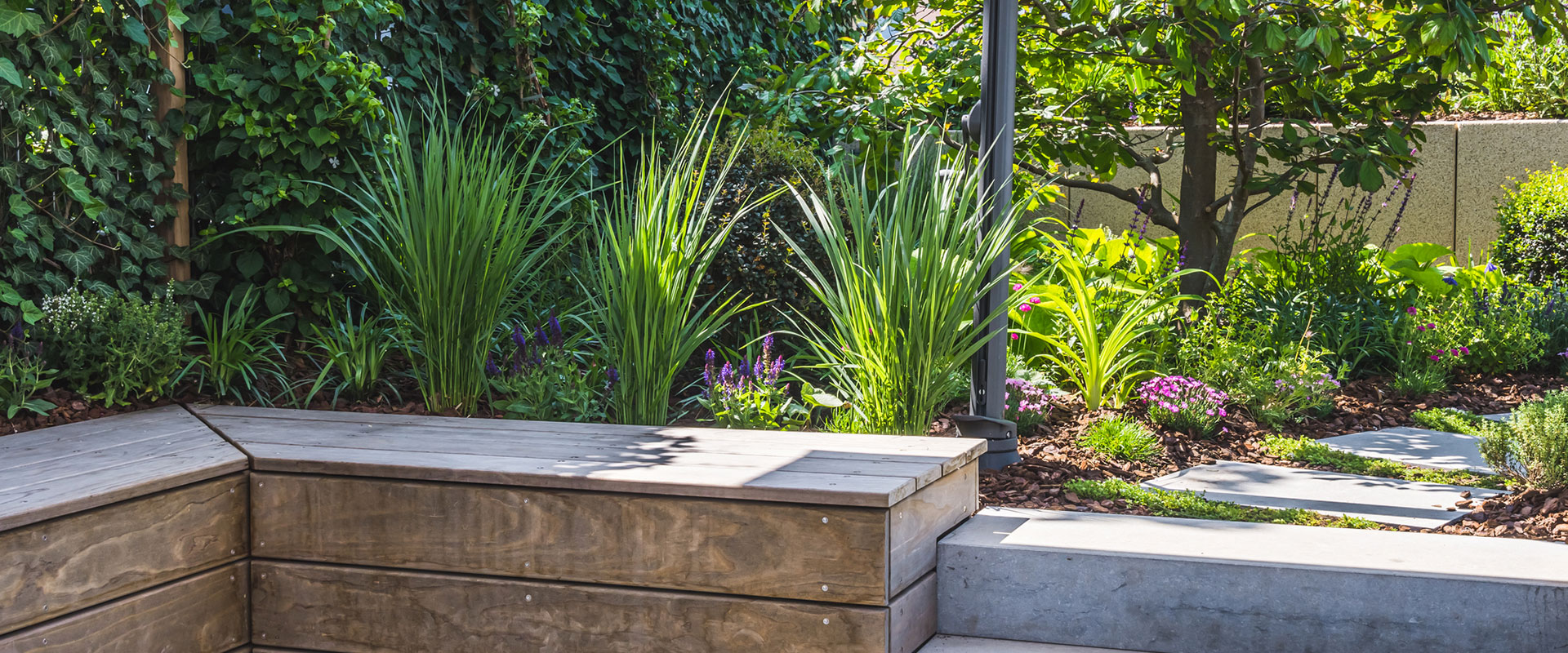 Commercial landscape with colorful flowers interspersed with small plants, vines, and tree.