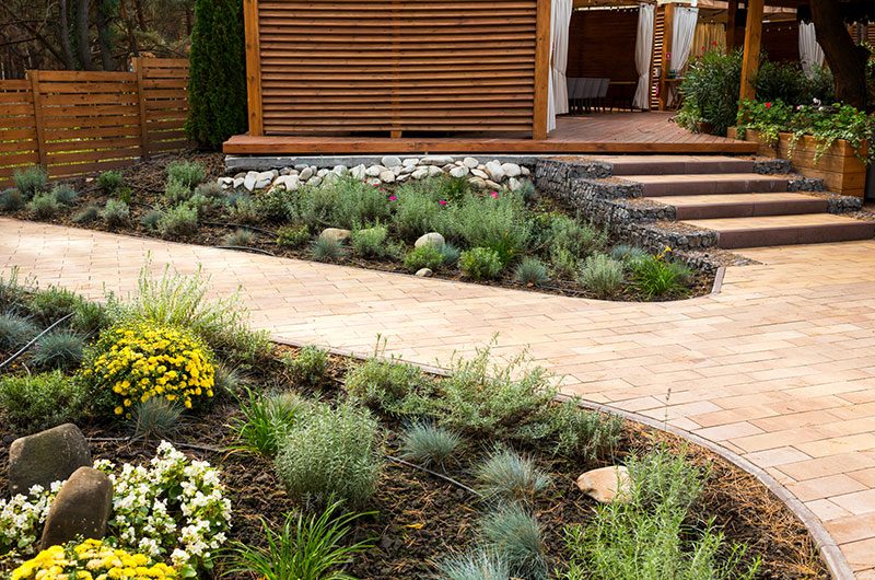 Eco-friendly plants and flowers with wood mulch ground cover, adjacent to brick walkway.